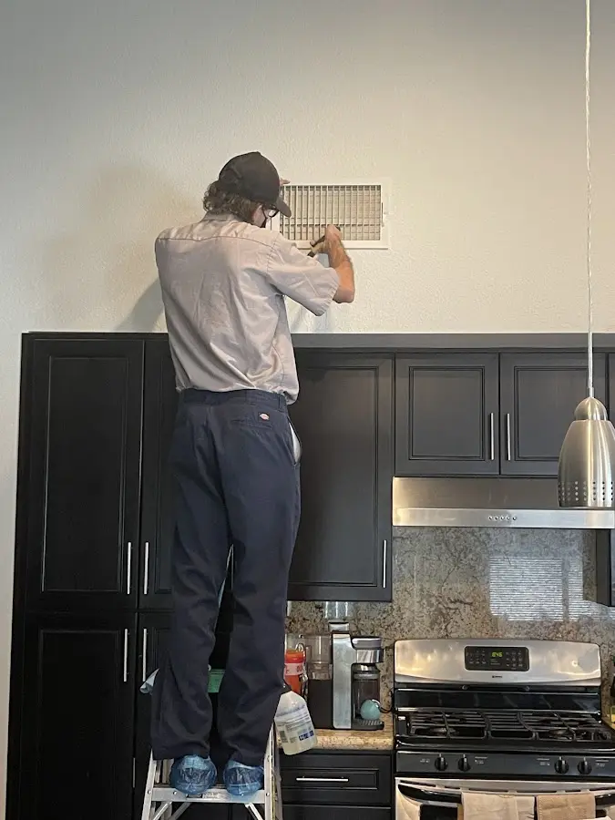Technician inspecting an air vent during HVAC service in Gleneagle